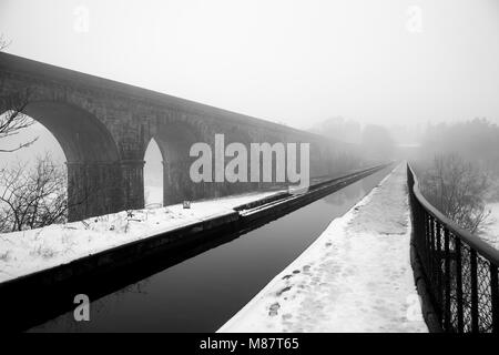 The Chirk aqueduct and railway viaduct disappear into the mist on the Llangollen canal during late winter Stock Photo