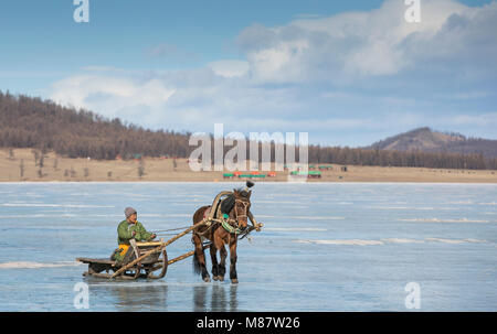 Hatgal, Mongolia, 2nd March 2018: mongolian man on a frozen lake with his horse sledge Stock Photo