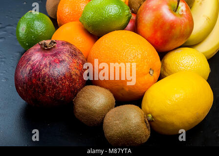 Variety of fresh fruits on dark background from slices of kiwi, bananas, aplle and orange ,copy space Stock Photo