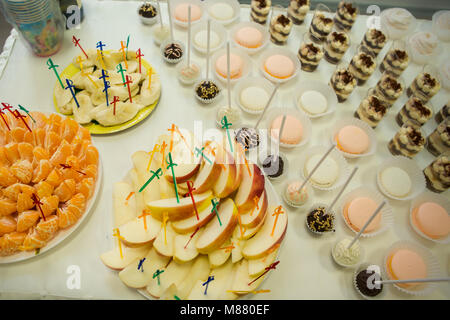 assorted fruits with skewers and tasty sweets served on white table Stock Photo
