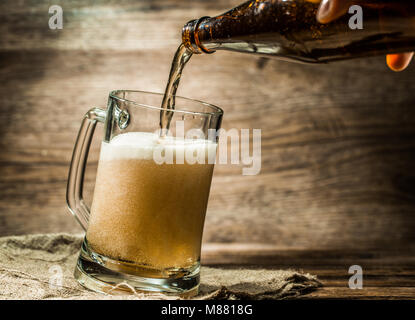 Foamy beer from bottle poured into mug Stock Photo