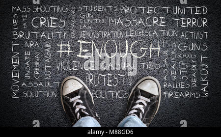 A teenager in jeans and canvas shoes standing on asphalt road with # ENOUGH word cloud. Concept of social movement to protest gun violence and mass sc Stock Photo