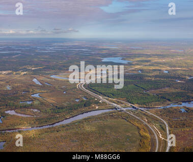 Highway and Railway crossing the river in West Siberia in autumn, top view. Two bridges cross forest river.