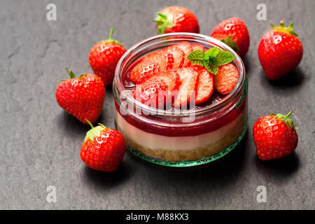 Mini  strawberry cheesecake in a glass pot on black stone background Stock Photo