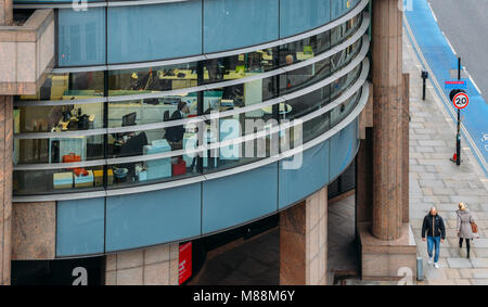 City of London professional workers at desks with computers as seen from a high perspective with view of pedestrians on street Stock Photo