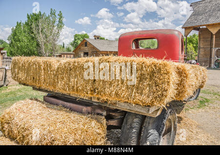 Old, flatbed truck with a red cab loaded with fresh hay Stock Photo