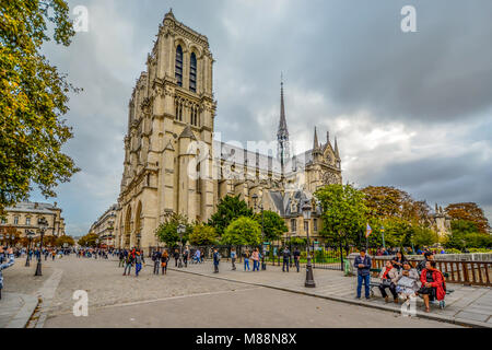 The gothic Notre Dame Cathedral on ile de la cite in Paris France with tourists and clouds in autumn, taken from the Pont au Double bridge Stock Photo