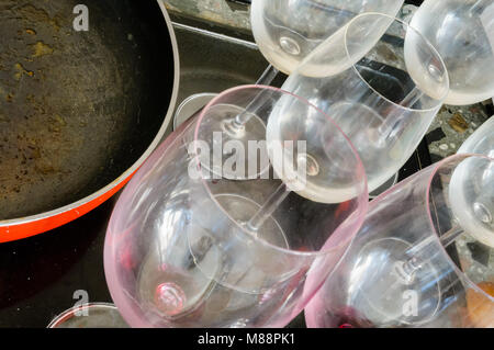 Dirty empty wine glasses and a red pan, after a good dinner, are waiting to be washed Stock Photo