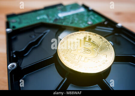 Cryptocurrency Golden Bitcoin on hard disk drive with blur background Stock Photo