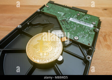 Cryptocurrency Golden Bitcoin on hard disk drive with blur background Stock Photo