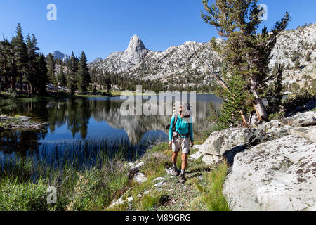 CA03402-00...CALIFORNIA - Vicky Spring hiking through the Rae Lakes area with Fin Dome in the distance, Kings Canyon National Park. (MR# S1) Stock Photo