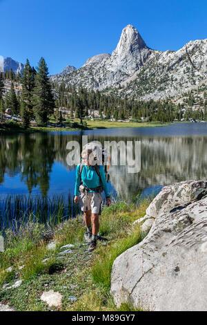 CA03404-00...CALIFORNIA - Vicky Spring hiking through the Rae Lakes area with Fin Dome in the distance, Kings Canyon National Park. (MR# S1) Stock Photo