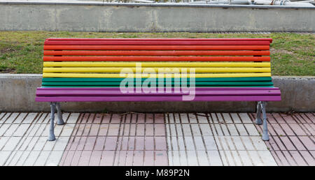 Bench painted in rainbow colors in the street Stock Photo