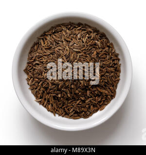 Caraway or cumin seeds in white ceramic bowl isolated on white from above. Stock Photo
