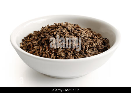 Caraway or cumin seeds in white ceramic bowl isolated on white. Stock Photo