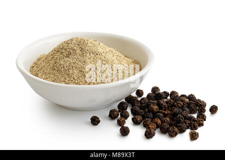 Finely ground white pepper in white ceramic bowl next to black peppercorns isolated on white. Stock Photo