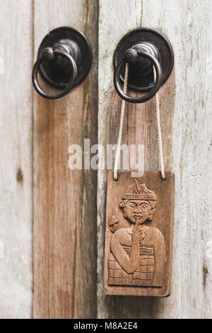 Wooden plate in balinese stile hanging on metal door knob. Textured background. Old rustic style. Don't disturb sign symbol Stock Photo