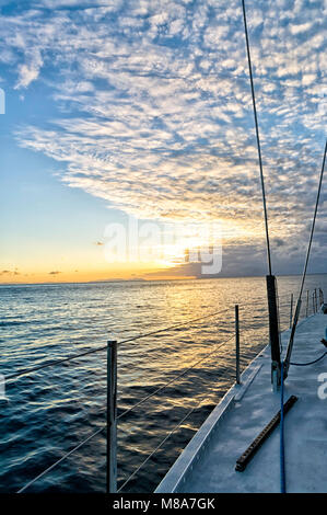View of a beautiful orange sunset from the deck of a sailing boat in the Australian sea near the Whitsunday's islands. Concept for quite, freedom Stock Photo