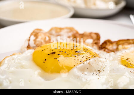 Traditional Israeli Breakfast with two fried eggs, yellow cheese, salad, a fresh roll and a cup of cappuccino. Closeup on the fried eggs Stock Photo