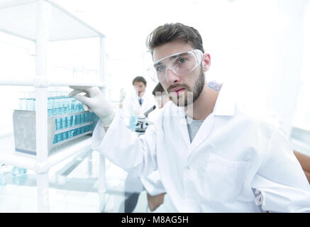 Young male scientist looking at a sample in a test tube side vie Stock Photo