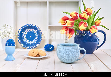 Cup of coffee and cookies on white table with red tulips and springtime decorations Stock Photo