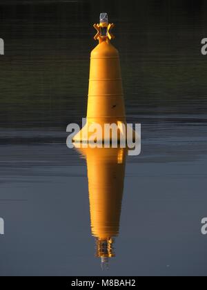 A yellow marker buoy reflected in the waters at Kennacraig Ferry Terminal on the Kintyre Peninsula in Argyll & Bute. Stock Photo