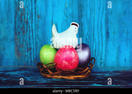 White chicken salt shaker and multicolored painted eggs on vintage wooden background. Easter's decorative ornaments. Background. chicken hen incubates Stock Photo