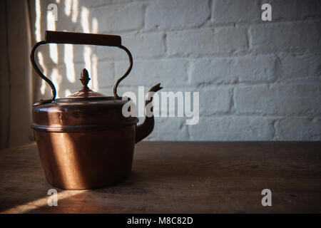 Old copper kettle on the wooden table . Stock Photo