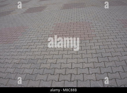 Texture of gray and yellow patterned paving tiles on the ground of street, perspective view. Cement brick squared stone floor background. Concrete pav Stock Photo