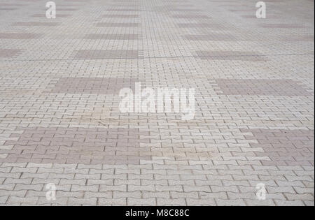 Texture of gray and yellow patterned paving tiles on the ground of street, perspective view. Cement brick squared stone floor background. Concrete pav Stock Photo