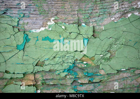 Flaky green paint on the wall. Wall with old peeling and cracked paint. Stock Photo