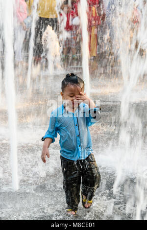 A young boy plays in the water from a street fountain, Ho Chi Minh City, Saigon, Vietnam Stock Photo