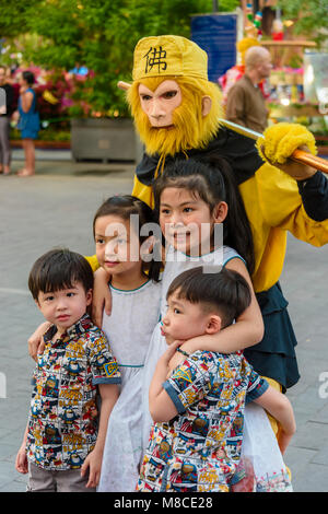 A group of children have a photograph taken with a man in a traditional monkey costume, Ho Chi Minh City, Saigon, Vietnam Stock Photo