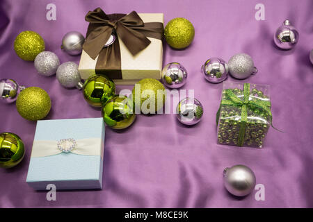 Three white gift boxes with red ribbons form on top of purple background Stock Photo