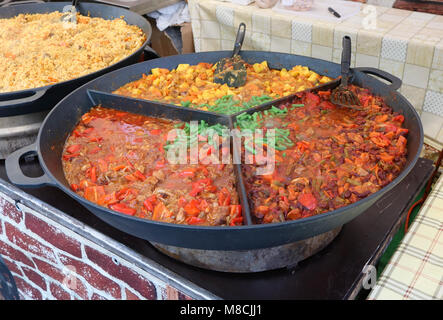 Fast street food - stewed haricot, paprika, tomato sauce  and potato with boiled beef in big frying pan. Spring fair holiday day outdoor shot Stock Photo