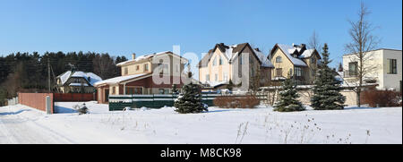 LITHUANIA , VILNIUS - MARCH 04, 2018: The frozen northern modern Pilaite village  near Lithuanian capital. The street, fences, snow, trees and the  wi Stock Photo