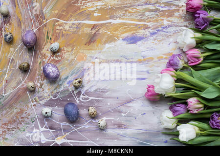 Painted chicken and quail eggs and tulips on stained background Stock Photo