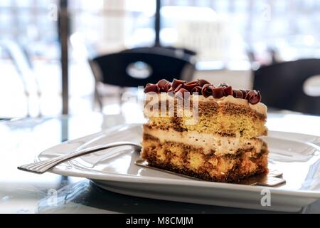 A piece of Tiramisu sitting on a plate waiting to be eaten. Stock Photo