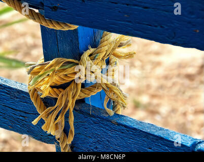 Thick jute yellow rope  hanging from blue painted wooden planks Stock Photo