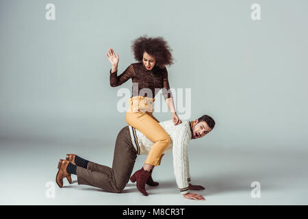 african american retro styled girl sitting on boyfriends back and having fun Stock Photo