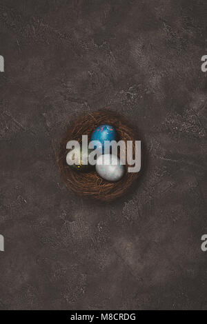 top view of nest with three painted easter egg on concrete table Stock Photo