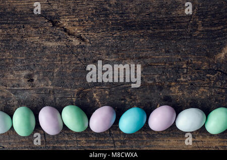 Easter chocolate eggs in pastel colors on old rustic wooden background with empty place for text. Top view. Copy space. Stock Photo