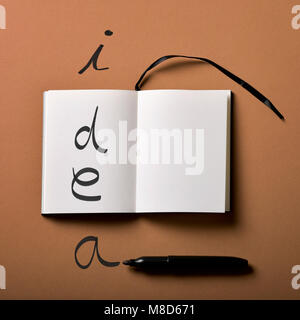 high angle view of an open notepad and a black marker pen, and the worid idea written with it Stock Photo