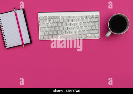Minimal computer keyboard notebook overhead on bright pink background Stock Photo
