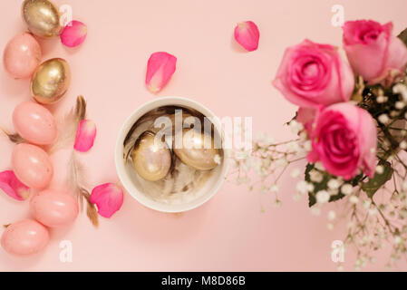 Easter eggs in a bowl. Pink and Gold Easter Eggs. Pastel Easter Concept with Eggs, Flowers and Feathers. Stock Photo