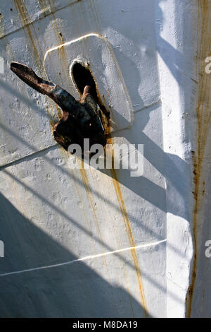 Black, rusty broken anchor on bow of an old iron boat Stock Photo