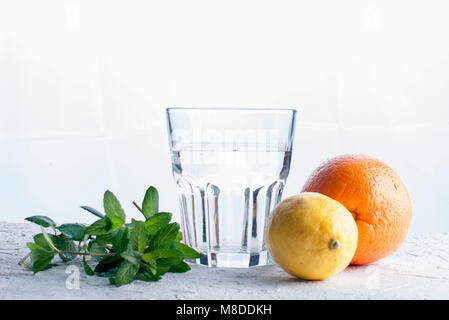 Ingredients for portion of Lemonade.Glass of water with ice, mint, lemon and lime surrounded by ice cubes Stock Photo