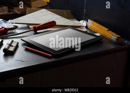 Tablet With Blank Screen On A Dark Cupboard With Tools In A Dirty Basement Stock Photo