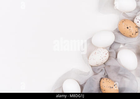 Stylish background with white and yellow easter eggs on silk fabric with space for text. Isolated on white background. Flat lay. Easter concept. Stock Photo