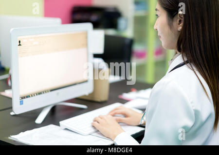 Asian woman doctor searching patient information from medical record system by using computer in hospital. Stock Photo